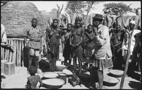 Group of people standing next to baskets of grain