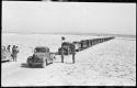 Five people standing, and trucks waiting to be loaded with salt