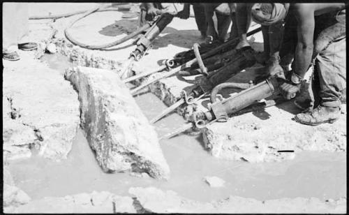 People breaking up pieces of salt with machinery