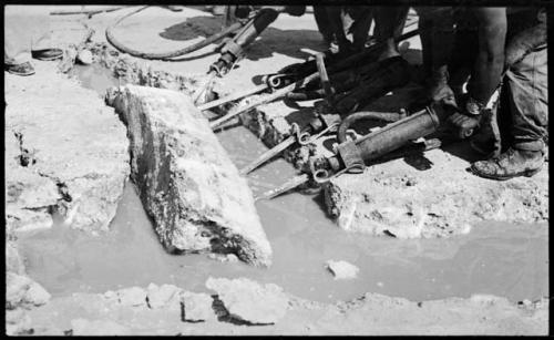 People breaking up pieces of salt with machinery