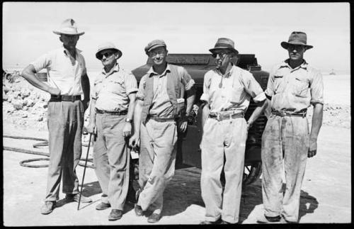 Five men standing in front of a truck