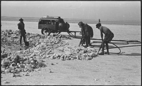 Men breaking up pieces of salt