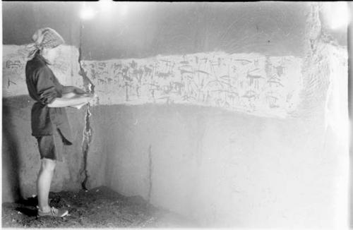 Elizabeth Marshall Thomas taking notes in the hut with wall drawings