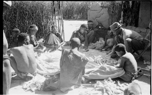 Group of people, including Lorna Marshall, in the Okwa hut with wall drawings