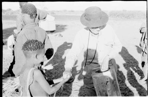 Group of men receiving food from Lorna Marshall