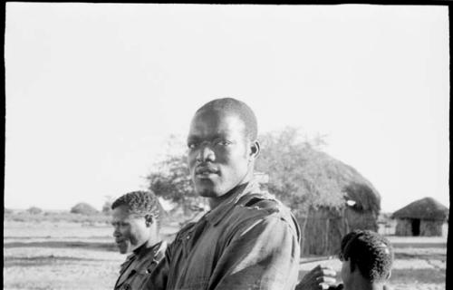 Man standing next to an expedition member, with a hut in the background