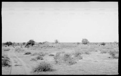 Group of people standing in Boys's kraal (clearing around huts) at Okwa