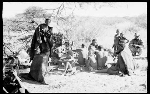 Group of people sitting and standing under a tree