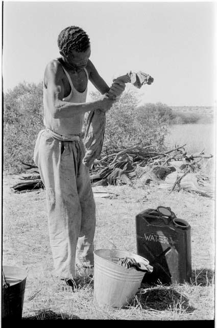 /Gishay washing his clothes using a bucket filled with water