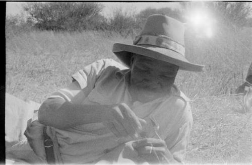 Chuana sewing while reclining on the ground