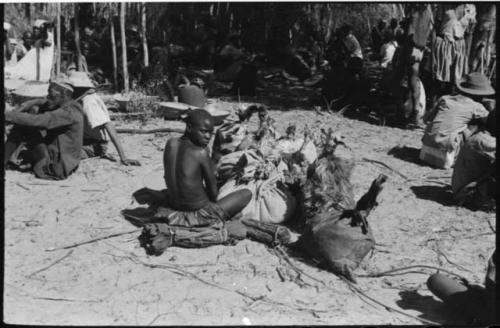 Woman sitting and looking at camera, with sacks on the ground next to her