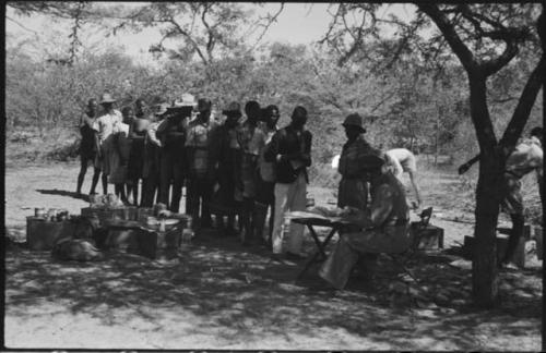 Group of men and women standing in line, possibly to pay grain tax to government official