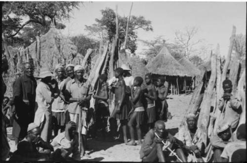 Group of people sitting and standing near a fence