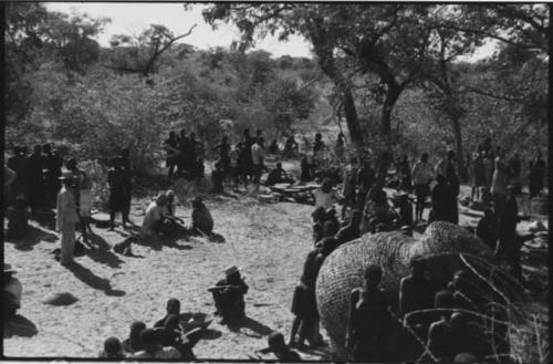 Group of people sitting and standing outside kraal