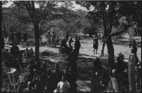 Group of people sitting and standing outside kraal