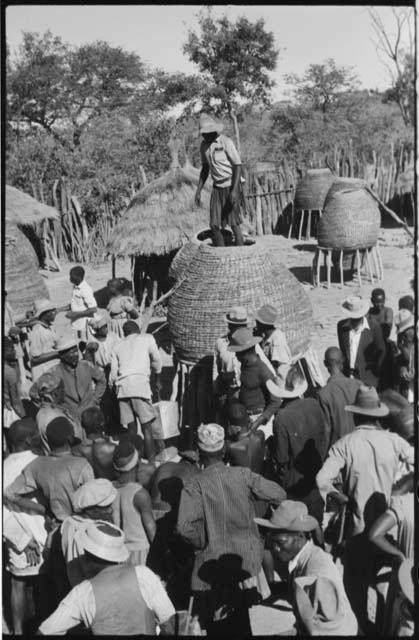 Group of people standing in front of storage baskets, and a man standing on top of one