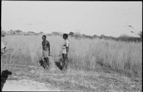 Two men standing and holding bows and arrows