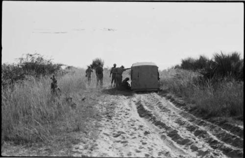 Men standing next to a truck stopped in the sand