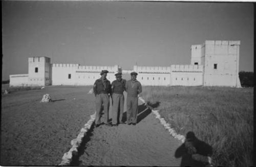 Three men standing in front of Fort Namutoni