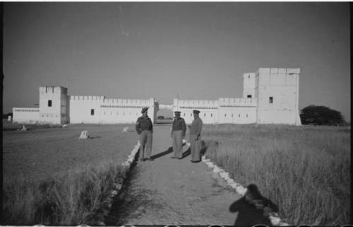 Three men standing in front of Fort Namutoni