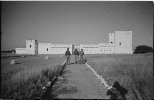 Three men standing in front of Fort Namutoni