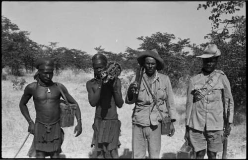 Four men standing and holding guns and cases