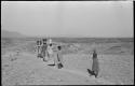 Group of people walking and carrying containers of tin ore on their heads