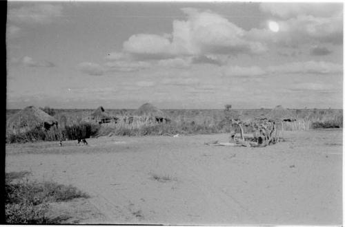 Three people standing in front of a hut