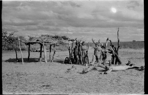 Two people standing out in front of a hut