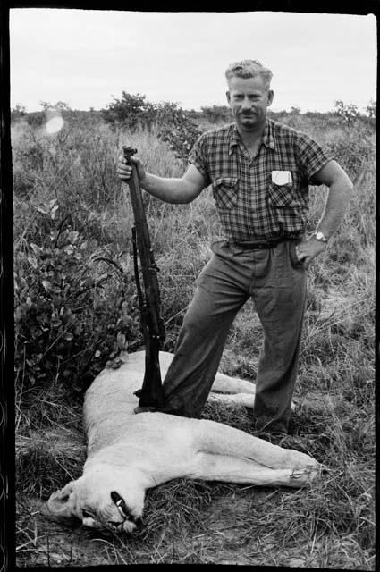 Theunis Berger standing with a gun over a dead lion