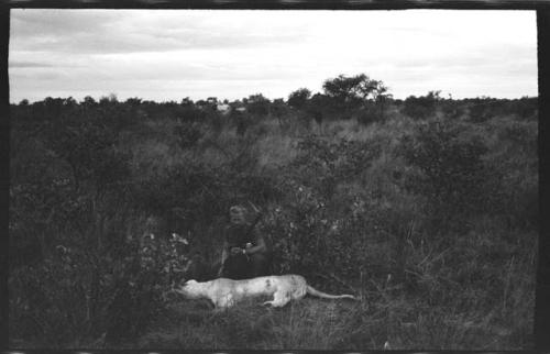 Theunis Berger with a gun kneeling behind a dead lion