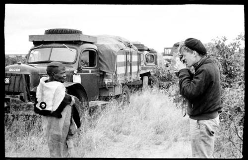 John Marshall taking a picture of a man wrapped in animal skins