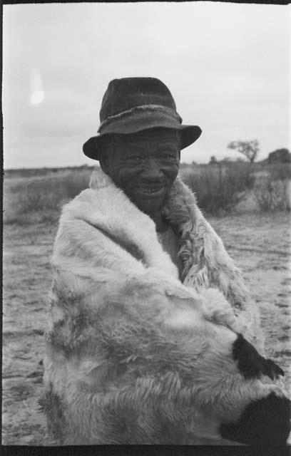 Seated man wearing animal skins and a hat