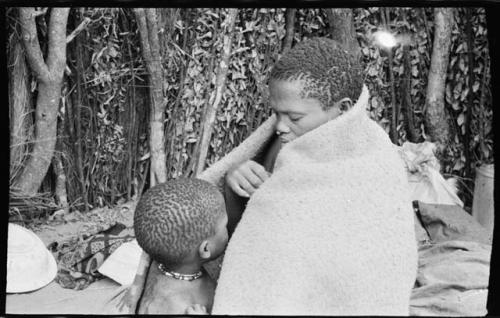 Woman and child sitting wrapped in a kaross