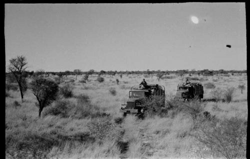 Two of the expedition trucks driving through tall grass