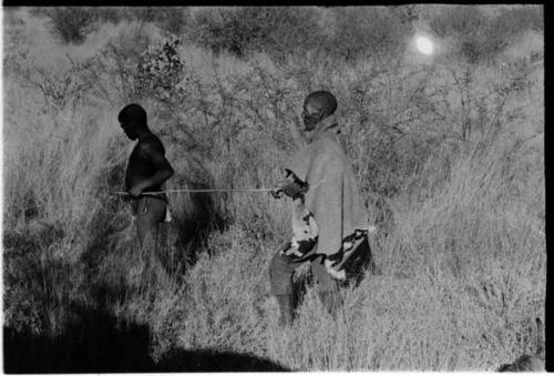 Elderly blind man led by a boy using a long stick