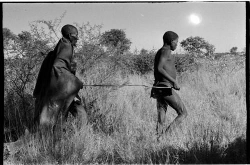 Elderly blind man led by a boy using a long stick