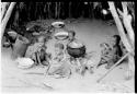 Four seated children beside a cooking pot