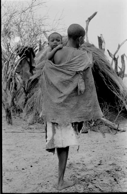 Woman carrying her child, view from the back