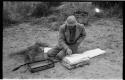 Robert Story sitting on the ground, packing specimens