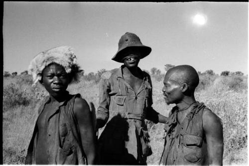 Headman wearing a hat, standing with two other men