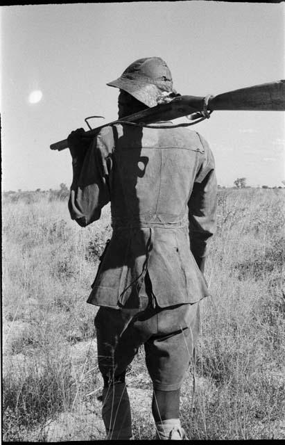 Headman carrying a gun over his shoulder, view from behind