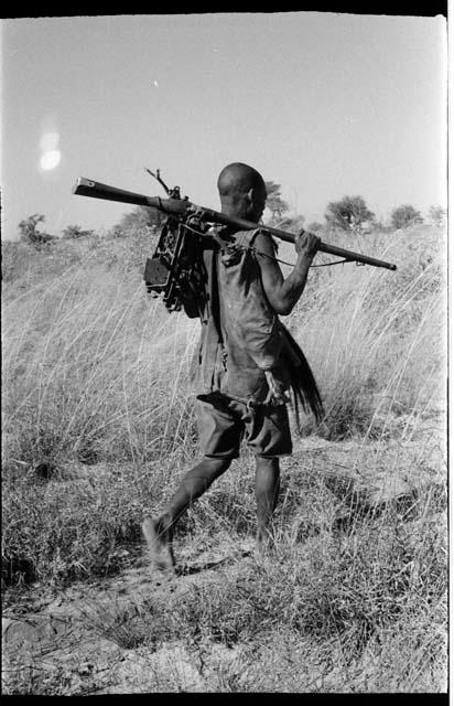 Man carrying animal traps and a gun