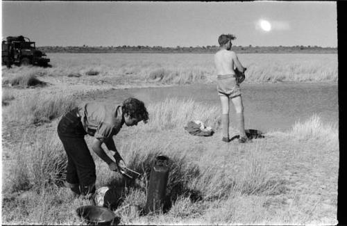 Two expedition members, one changing clothes, one getting water