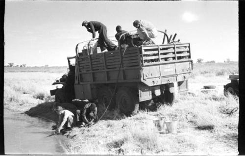 Expedition members filling barrels with water from the pan