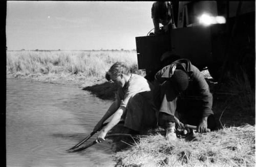 John Marshall and expedition members filling barrels with water from the pan, close-up