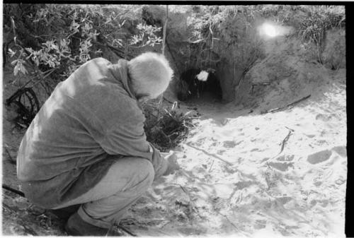 Laurence Marshall crouching looking into a hole