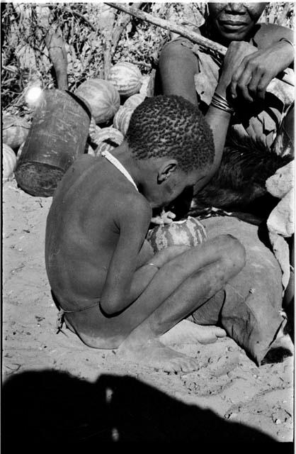 Boy sitting eating a tsama melon