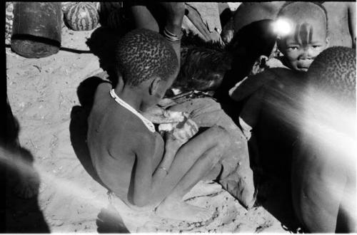 Child sitting eating a tsama melon. rear view