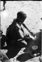 Woman seated scraping a tsama melon